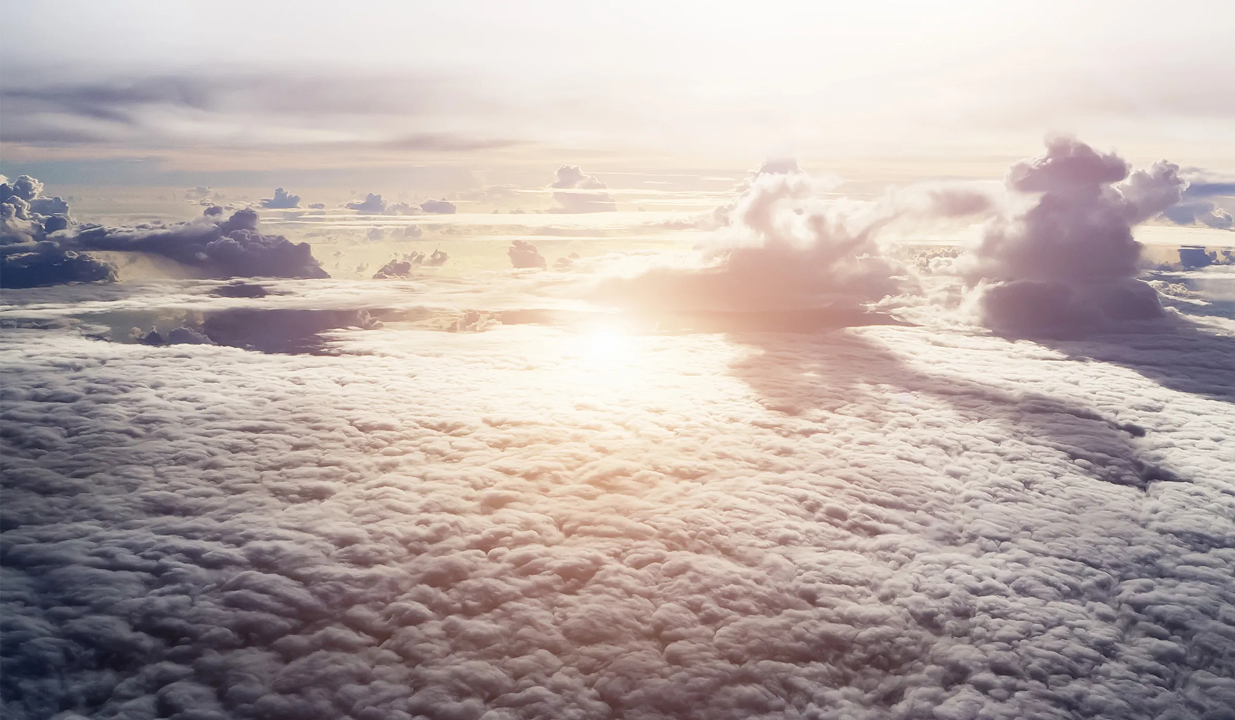 Blick über strahlende Wolken, Sonne am Horizont. Weiche Pastelltöne am Himmel. Erhabene Szenerie.